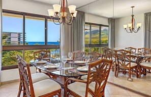 A dining area with a glass table, wicker chairs, and a view of the ocean. - Maui Resort Rentals: Expansive 5BR Oceanview Retreat for 16 on Kaanapali Beach (Lahaina)