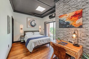 Ein modernes Schlafzimmer mit Bett, Schreibtisch und großem Fenster.