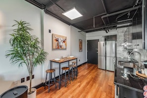 Een moderne keuken met een roestvrijstalen koelkast, een eethoek met een houten tafel en stoelen, en een potplant.