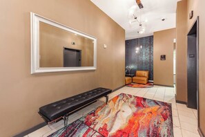 Eine Hotelhalle mit einer Bank, einem großen Spiegel, einem gemusterten Teppich und einer Sitzecke mit einem Sessel.