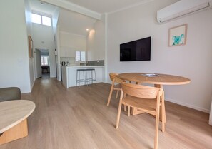 A modern living space with a dining area, kitchen, and a large window. - Serenity Seas 1 Bed Escape-close to Hastings St (Noosa Heads)