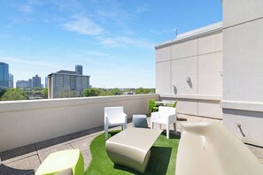 A rooftop terrace with outdoor seating, a slide, and a city view. - The Eighth | Luxury Penthouse in Fourth Ward (Charlotte)