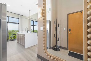 A modern kitchen with a large island, a ceiling fan, and a view of the outdoors. - The Eighth | Luxury Penthouse in Fourth Ward (Charlotte)