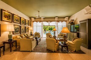 A spacious living room with multiple sofas, a television, and framed artwork on the walls.