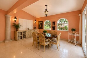 A dining area with a round table, chairs, and a cabinet with decorative items.