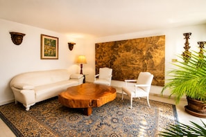 A living room with a sofa, two chairs, a coffee table, a lamp, a large painting, and a patterned rug. - Casa Carlota with Pool & Garden (Cuernavaca)