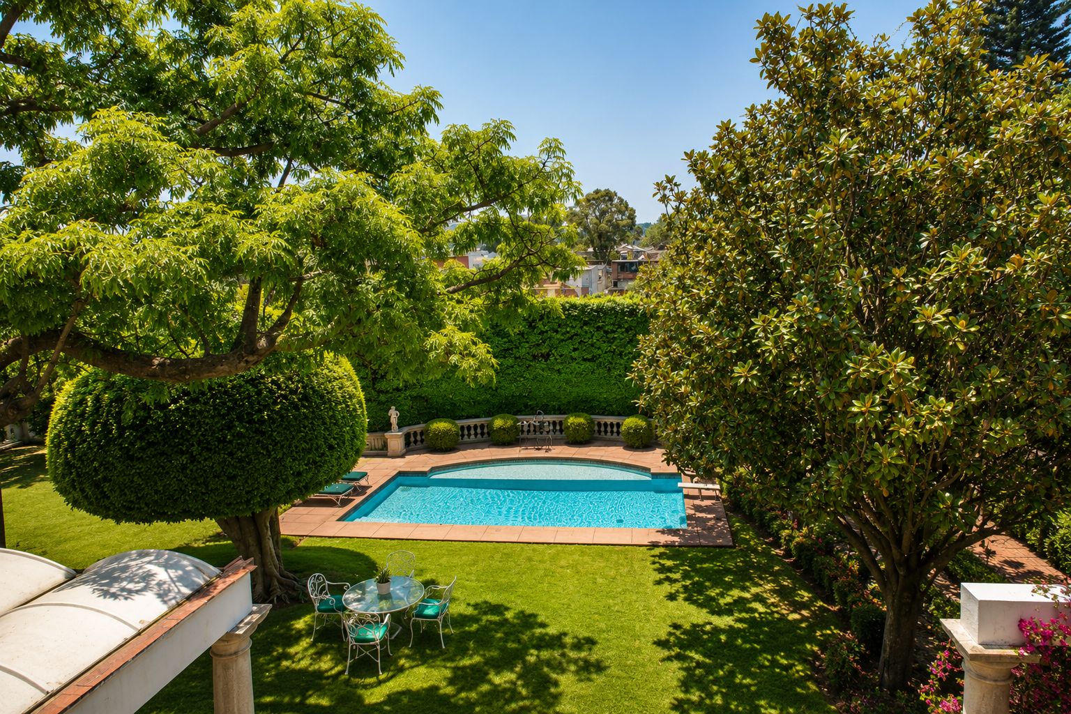 A swimming pool surrounded by well-maintained grass and trees, with a clear view of the surrounding area.