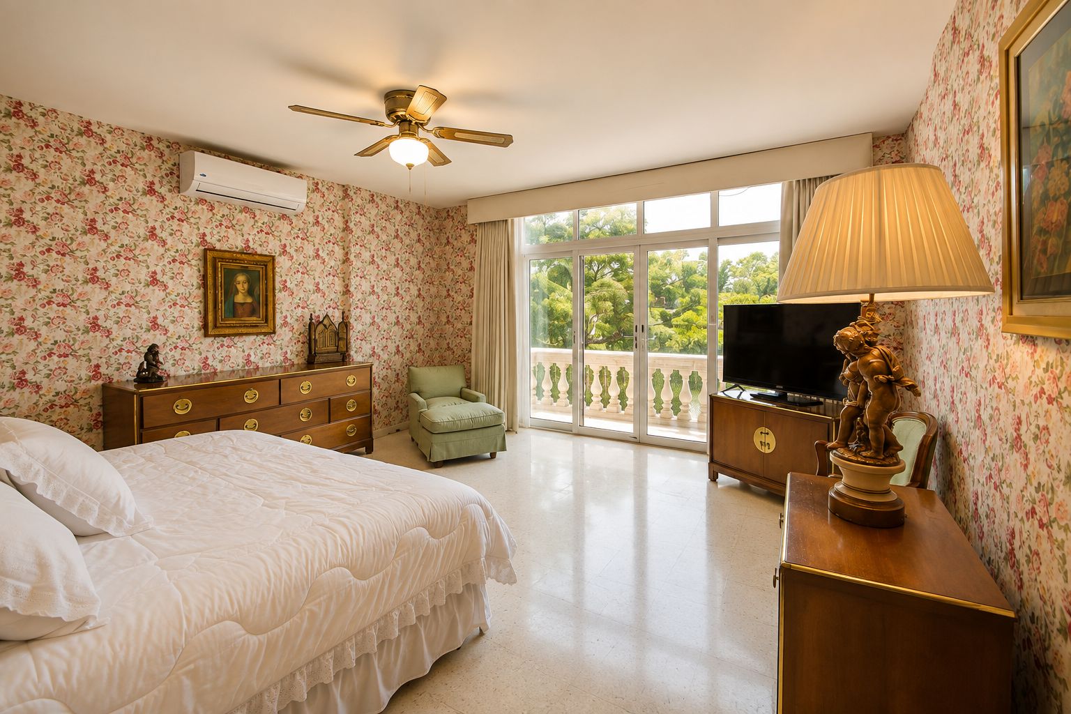 Un dormitorio con cama, cómoda, televisor y un balcón con vistas.