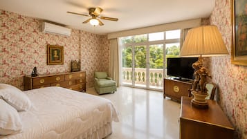 Un dormitorio con cama, cómoda, televisor y un balcón con vistas.