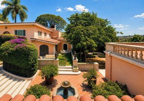 A courtyard with a fountain, a seating area, and a view of the surrounding landscape.