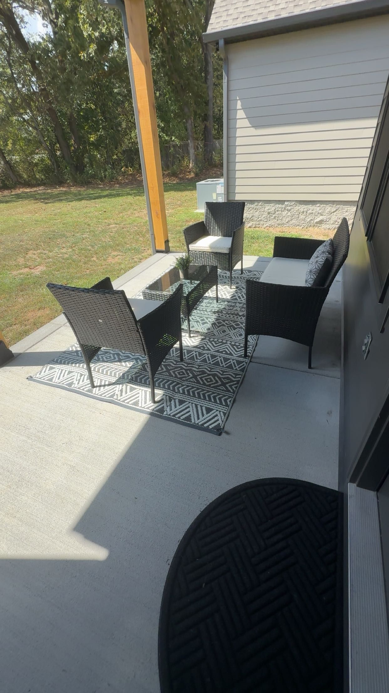Une terrasse extérieure avec un barbecue, un coin salon et un tapis à motifs.