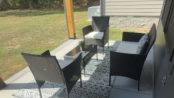 Une terrasse extérieure avec un barbecue, un coin salon et un tapis à motifs.