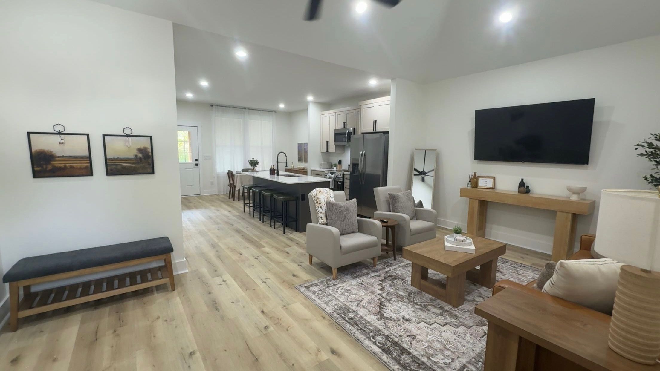 Un salon moderne avec un canapé, des fauteuils, une table basse et un téléviseur.