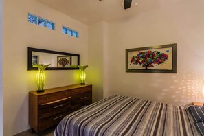 A bedroom with a bed, a dresser, a mirror, and a wall-mounted artwork. - Modern penthouse, 2bd/2ba, in Zona Romantica (Puerto Vallarta)