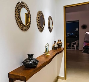 A hallway with a wooden console table, three wall-mounted mirrors, and decorative vases. - Modern penthouse, 2bd/2ba, in Zona Romantica (Puerto Vallarta)