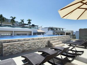 Zona de piscina al terrat amb gandules i una paret de pedra.