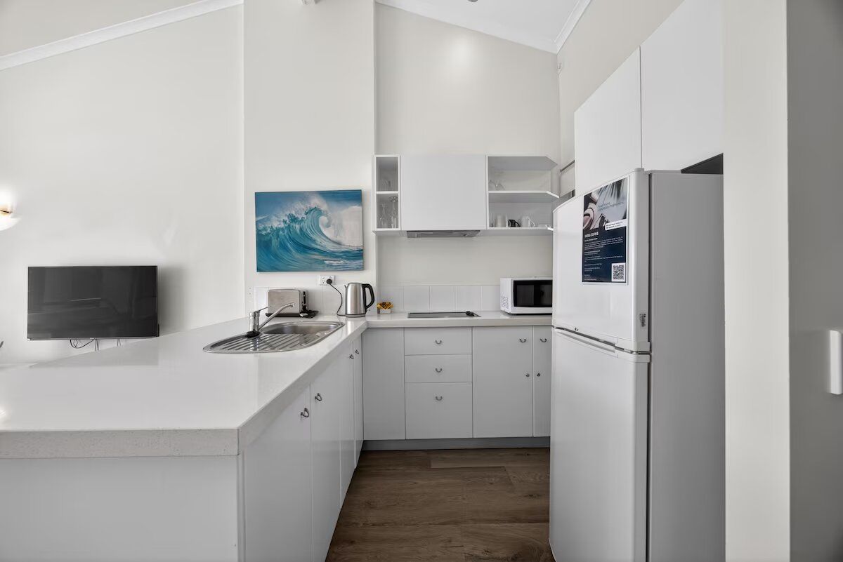 Een moderne keuken met witte kasten, een ingebouwde magnetron en een waterkoker.