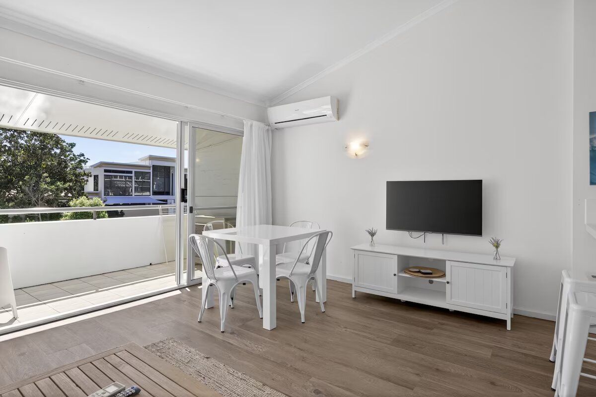 Un salon moderne avec un téléviseur blanc, une table à manger et des chaises.