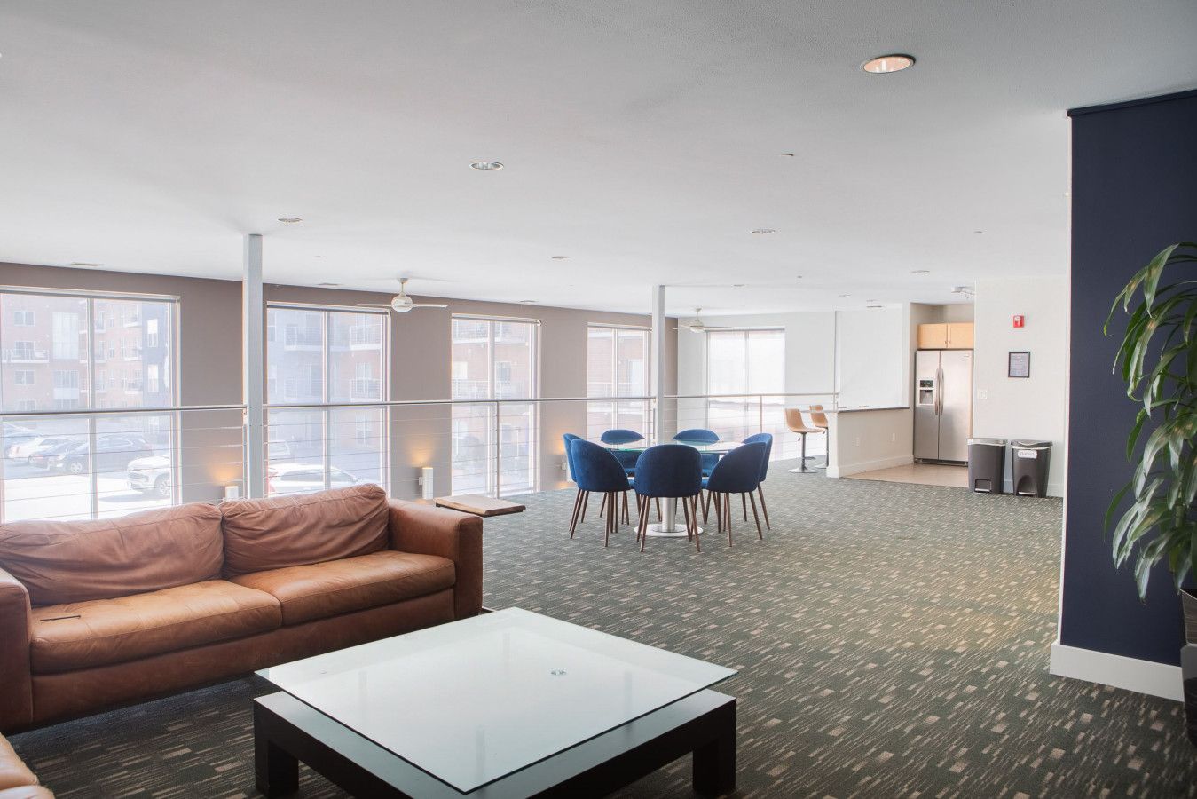 A spacious hotel lobby with a leather sofa, a glass-top coffee table, and a blue round table with chairs.