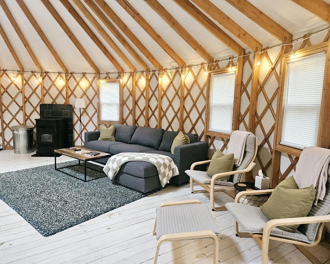 Un intérieur chaleureux avec un canapé, des fauteuils, une table basse et une cheminée.