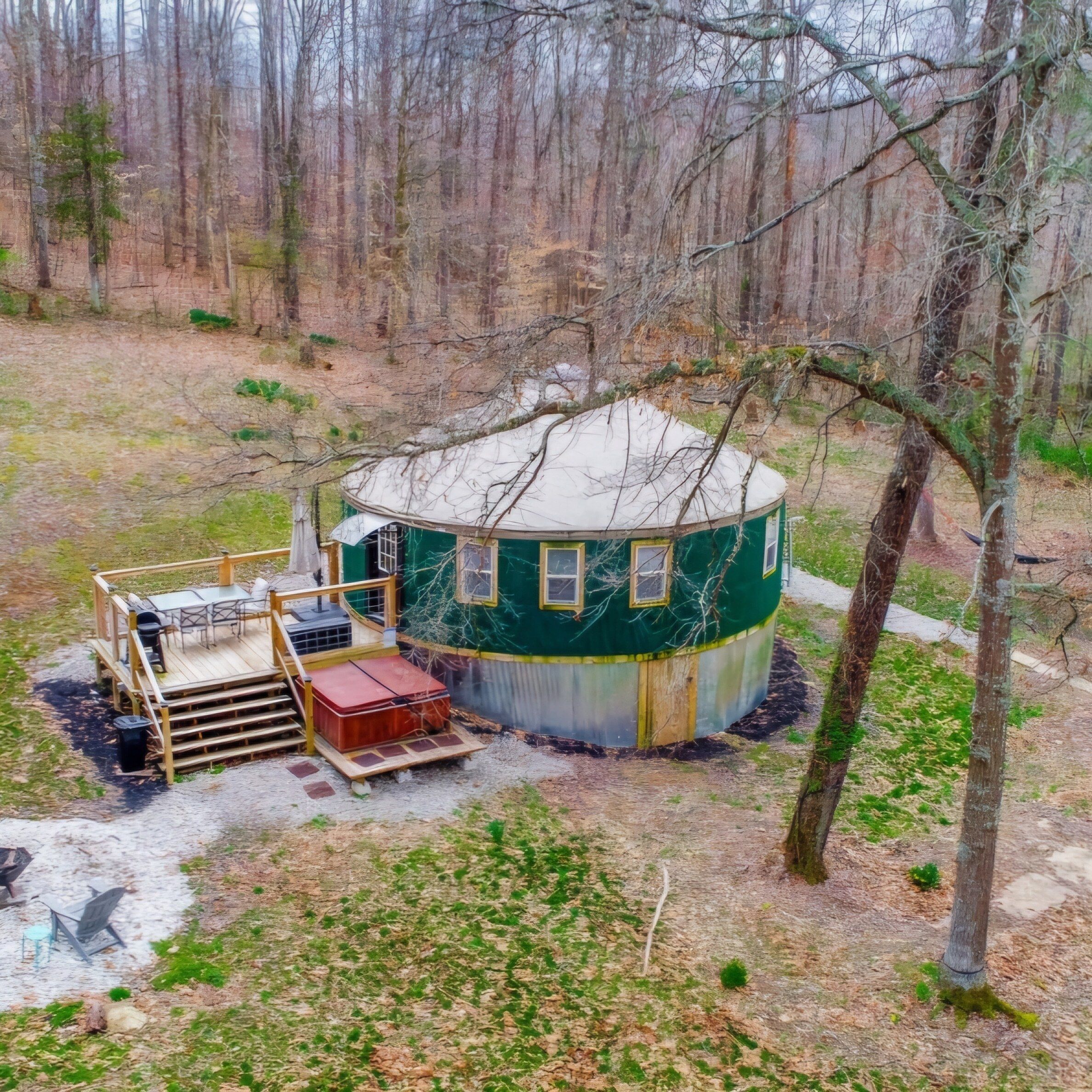 A circular cabin with a deck and a small outdoor seating area.