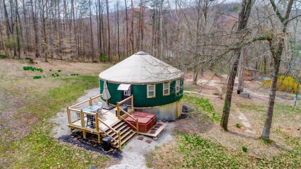 A circular cabin with a covered deck and a small outdoor area.