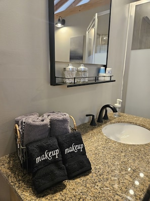 A bathroom with a granite countertop, a sink, a mirror, and a towel rack with towels.