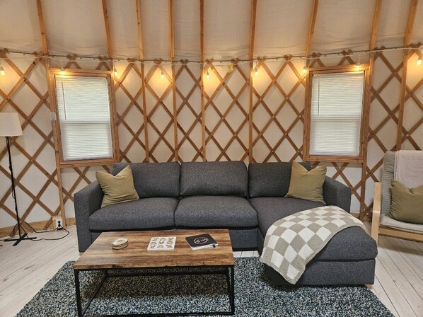 A cozy living room with a grey sofa, a wooden coffee table, and a patterned rug.
