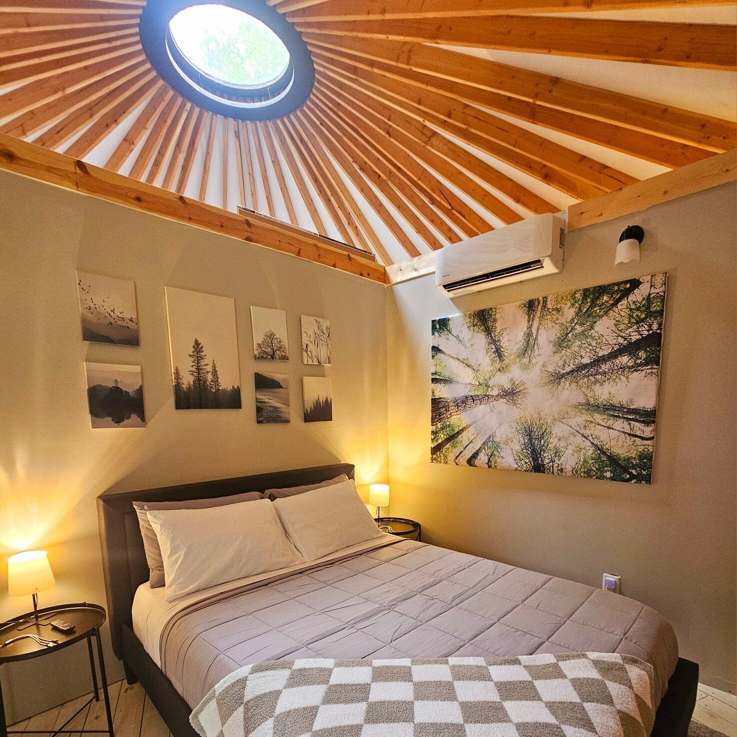 A bedroom with a skylight, a bed, a nightstand, and wall art.