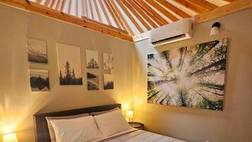 A bedroom with a skylight, a bed, a nightstand, and wall art.