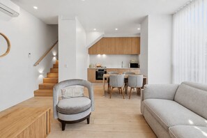 A modern living room with a sofa, a chair, and a dining area with a table and chairs. - Richmond Lumiere by Ready Set Stay (Richmond)