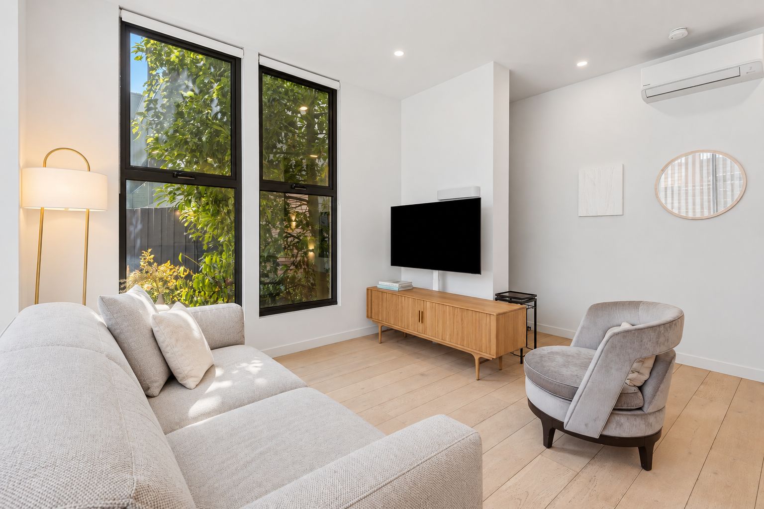 Een moderne woonkamer met een bank, een televisie, een bijzettafeltje en een stoel.