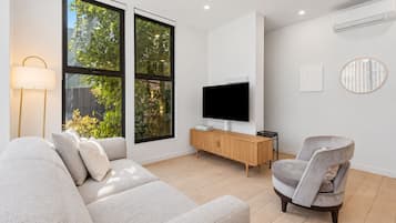 Ein modernes Wohnzimmer mit einer Couch, einem Fernseher, einem Beistelltisch und einem Sessel.