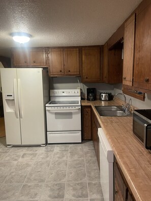 A kitchen with wooden cabinets, a white refrigerator, a stove, a microwave, and a dishwasher. - Cozy 3-bedroom home in welcoming Robbinsville, NC. (Robbinsville)