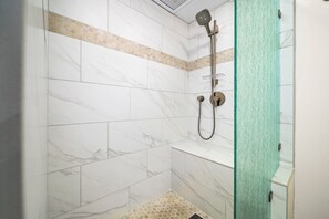 A shower area with white marble tiles and a glass partition. - Kaanapali Maui Eldorado D103 Garden View 2 BD (Lahaina)
