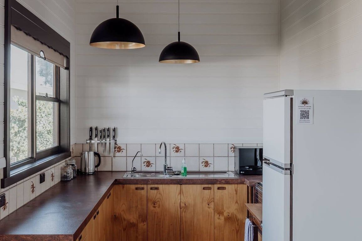 A kitchen with a wooden island, pendant lights, a refrigerator, and a window with a view.