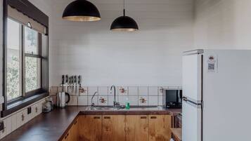 A kitchen with a wooden island, pendant lights, a refrigerator, and a window with a view.