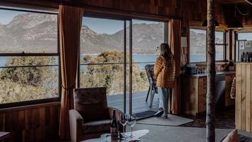 A room with large windows overlooking a mountainous landscape, a wooden interior, and a bar area.