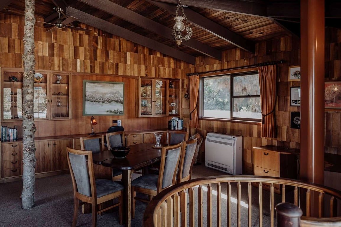 Een houten interieur met een eethoek, een open haard en een uitzicht door een raam.