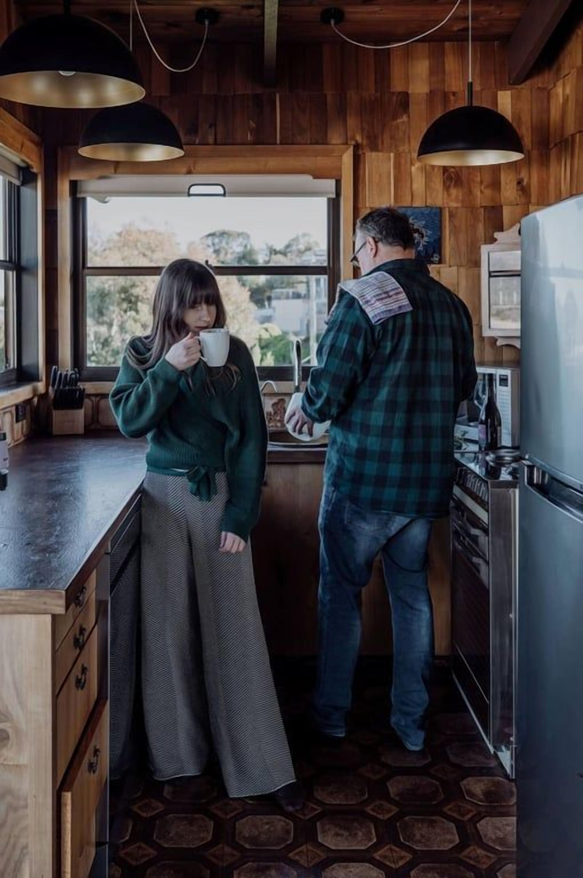 A wooden interior with a kitchen counter, a window, and a refrigerator.