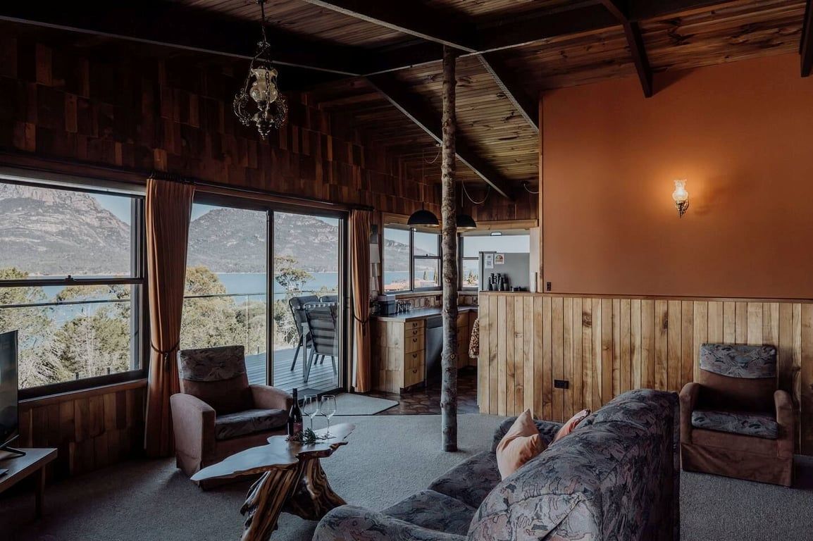 A cozy interior with a wooden ceiling, a dining area, and a seating area with a view of the outdoors.