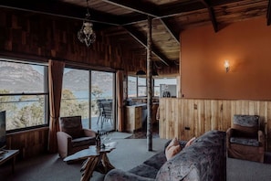 A cozy interior with a wooden ceiling, a dining area, and a seating area with a view of the outdoors.