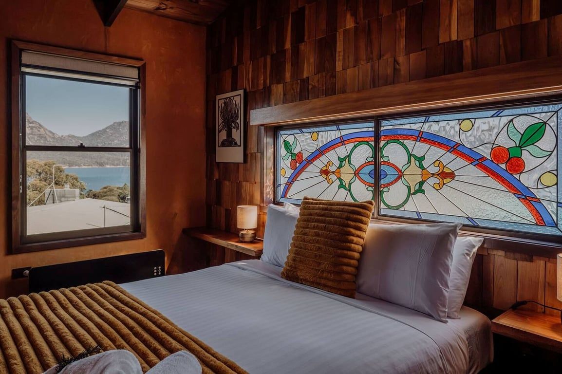 Um quarto com cama, janela com vista para o mar e uma janela de vitrais.