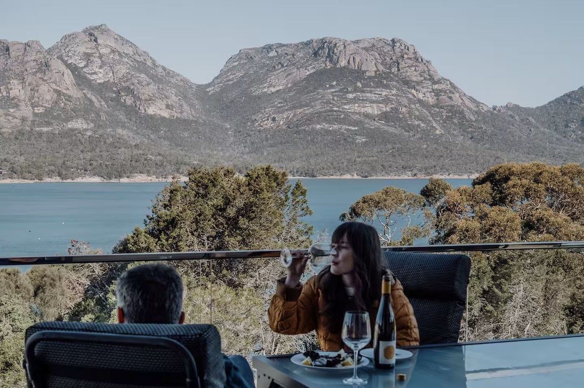 A dining table with a view of a mountainous landscape and a body of water.