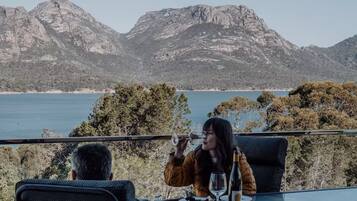 A dining table with a view of a mountainous landscape and a body of water.
