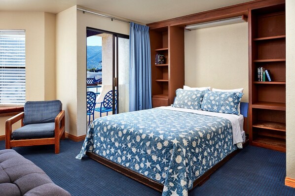 Une chambre avec un lit, une chaise, une bibliothèque et une vue sur l’extérieur, accessible par une porte coulissante.