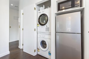 A laundry room with a washing machine, dryer, and a microwave above the dryer. - Corner Character 2BR at Dilworth with Balcony (Auckland Central)
