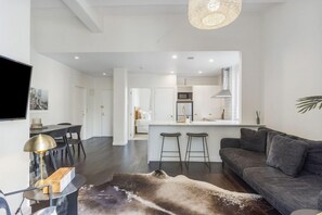 A modern living room with a dark grey sofa, a wooden coffee table, and a large animal print rug. - Corner Character 2BR at Dilworth with Balcony (Auckland Central)