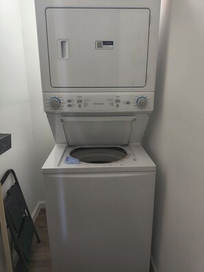 A front-loading white Frigidaire washer with a control panel, a QR code, and a small blue tray. - Furnished 2BR/2BA Houston Home - Gated Parking (Houston)