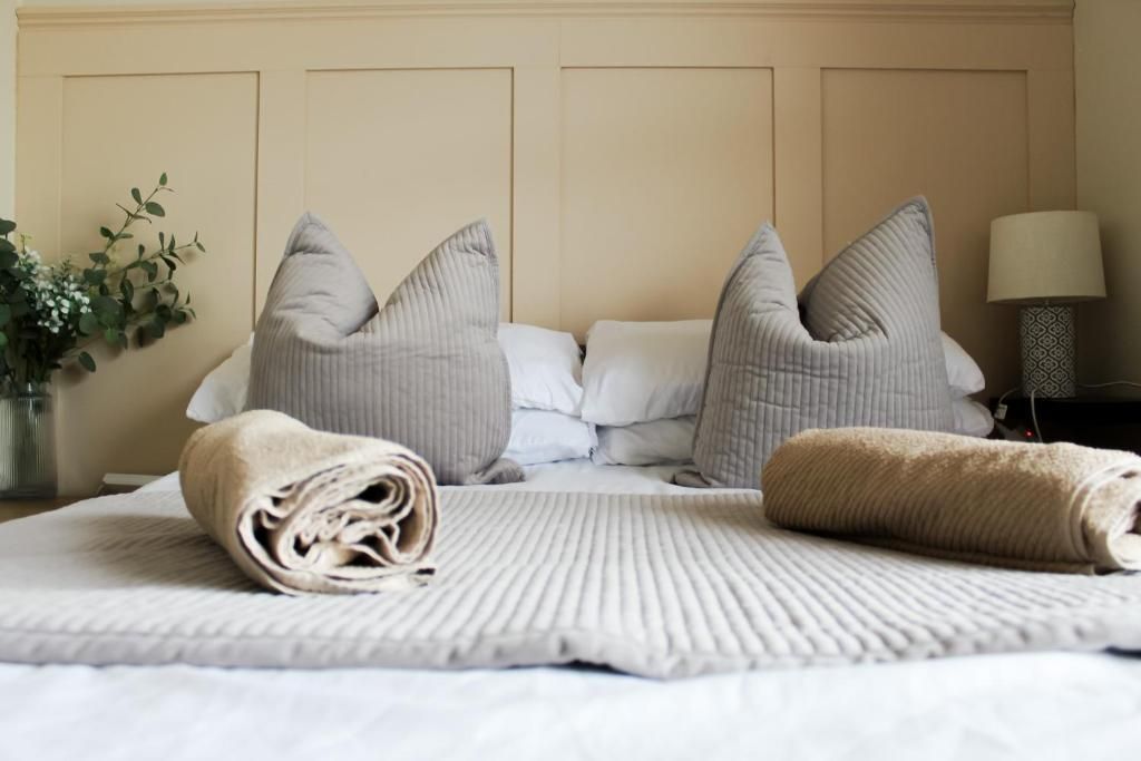 A neatly made bed with rolled towels, two pillows, and a bedside lamp.